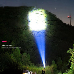 Handheld flashlight casting a bright beam outdoors at night
