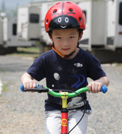 Red toddler safety helmet with ladybug face print and black chin strap