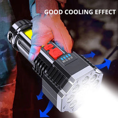 Hand holding a black flashlight with bright beam and red side switch