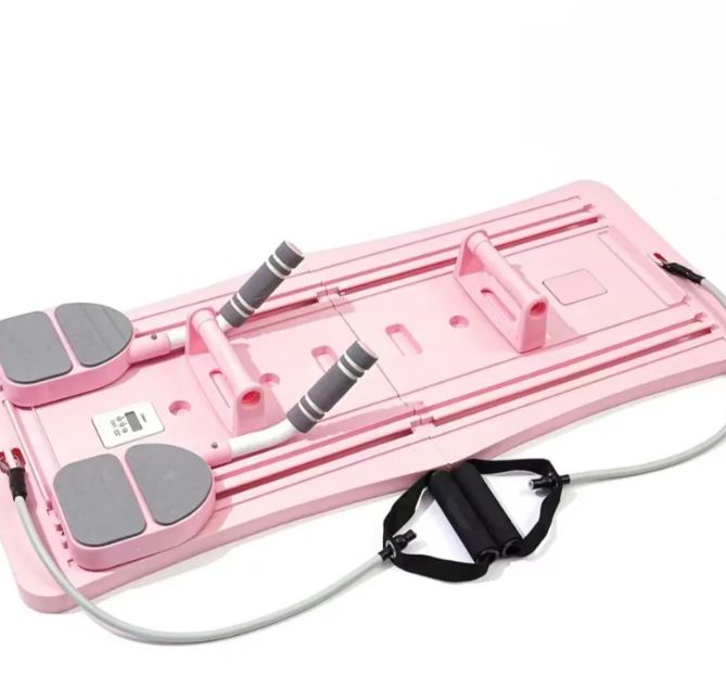 Pink compact Pilates sliding board with gray foot pads and black strap attachments